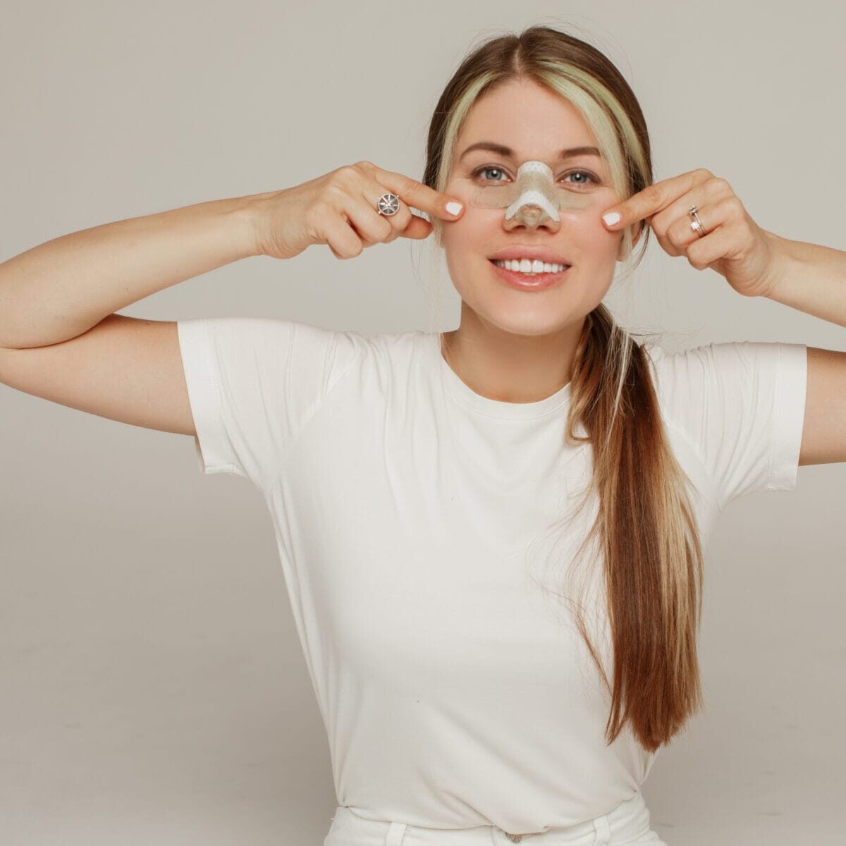 A young woman with a bandage on her nose after rhinoplasty rejoices
